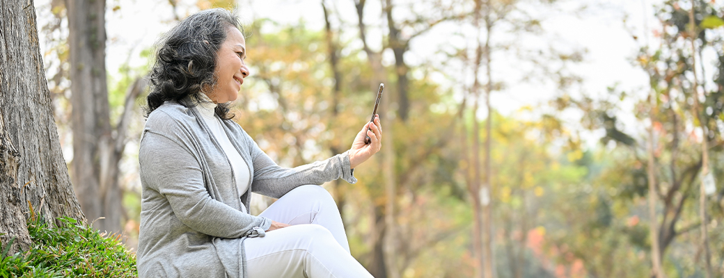 Image of middle-aged woman looking at her mobile phone outdoors